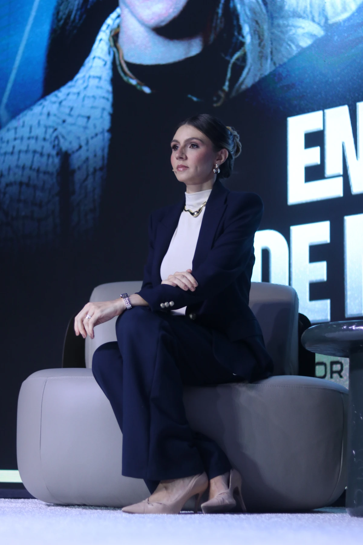 Mulher de blazer azul durante entrevista no palco.