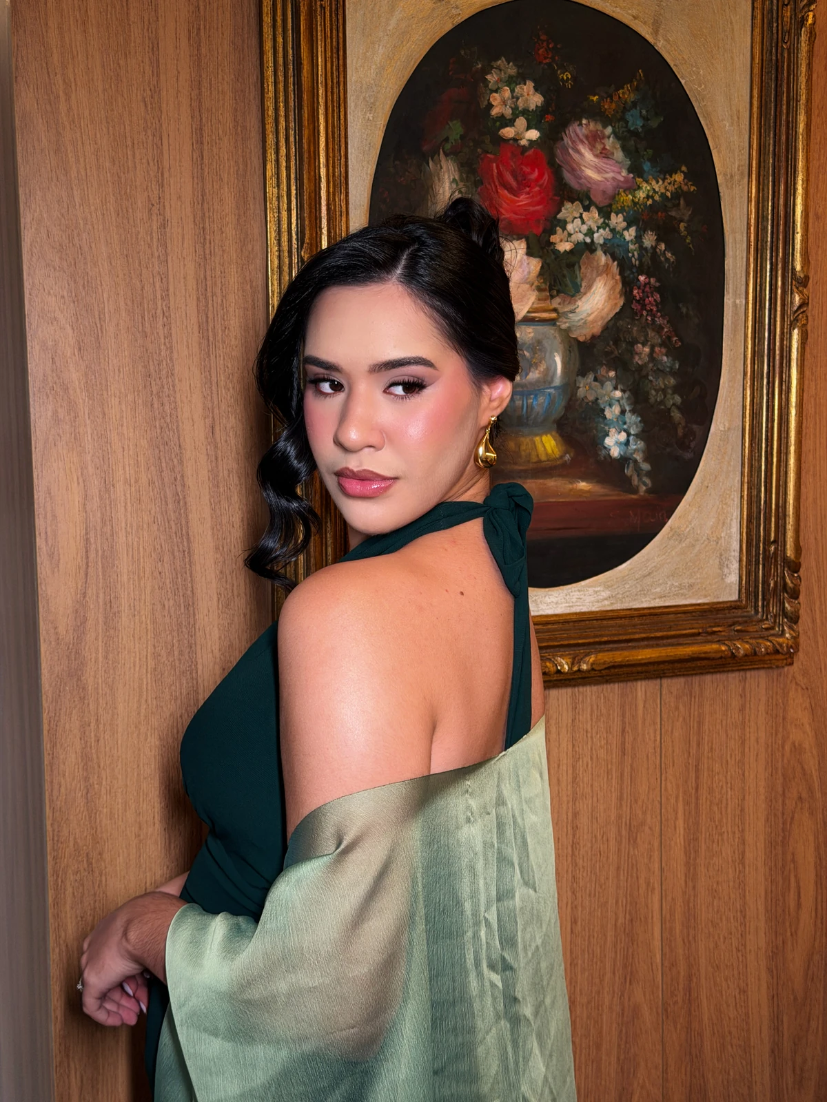 Retrato de perfil de cliente com vestido verde e cabelo preso.